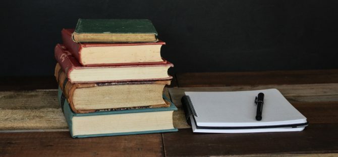 पुस्तकों का ढेर और शोध के लिए नोटपैड